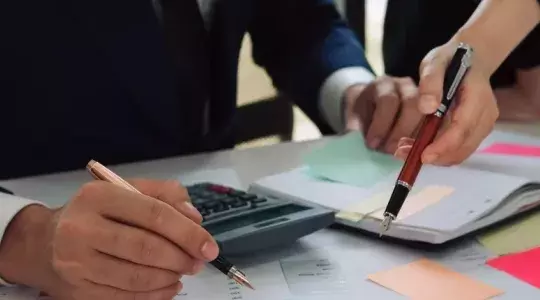 personnes tenants des stylos en train de calculer
