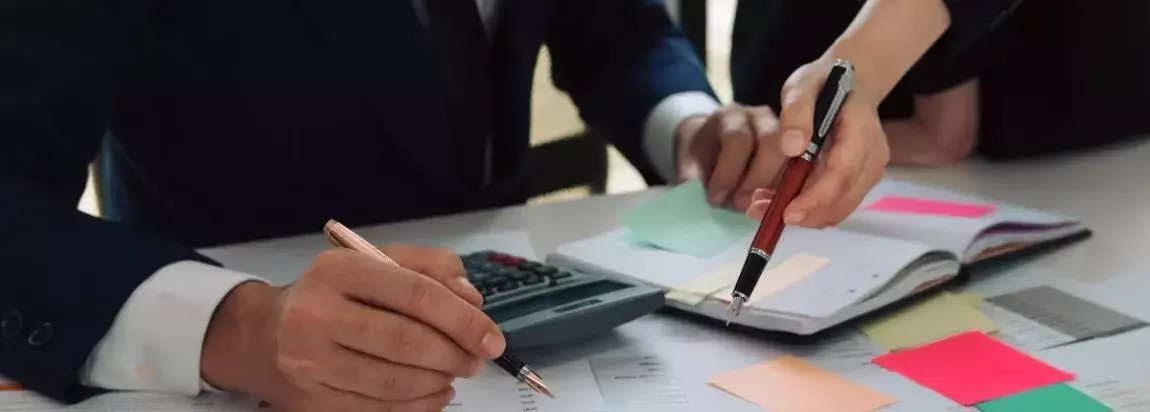 personnes tenants des stylos en train de calculer